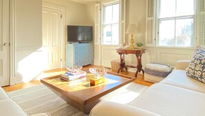 A living room with a wooden coffee table, a sofa, a television, and a lamp. - Stunning, Classic Renovated Greek Revival - few mins Walk to Main St & VH Ferry (Vineyard Haven)