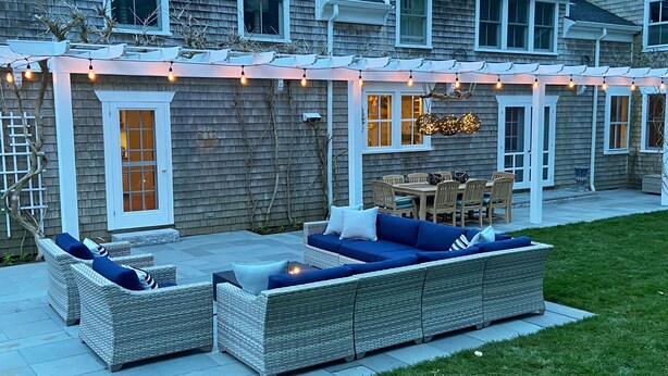 An outdoor patio with wicker furniture, a dining table, and string lights. - Stunning, Classic Renovated Greek Revival - few mins Walk to Main St & VH Ferry (Vineyard Haven)