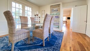 A dining area with wicker chairs, a glass table, and a blue patterned rug. - Stunning, Classic Renovated Greek Revival - few mins Walk to Main St & VH Ferry (Vineyard Haven)