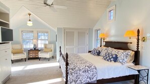 A bedroom with a bed, two chairs, a dresser, a television, and a ceiling fan. - Stunning, Classic Renovated Greek Revival - few mins Walk to Main St & VH Ferry (Vineyard Haven)