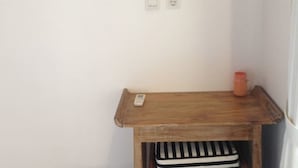 Une petite table en bois, une chaise à rayures, une télécommande et une tasse posés dessus.