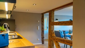 A modern kitchen with a wooden countertop and a view into a living area with a blue sofa and a dining table. - Lots of space for large families (Neusalza-Spremberg)