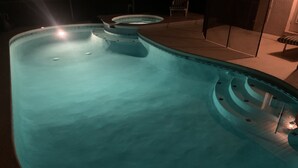 Une piscine au design incurvé et un petit jacuzzi.