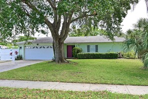 A single-story house with a red door, a garage, and a well-maintained lawn. - Tropical Luxury Escape – Heated Pool, Pets OK, IMG (Bradenton)