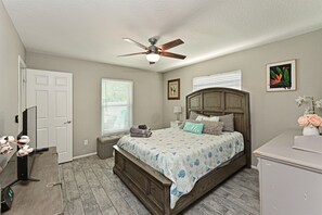 A bedroom with a bed, a ceiling fan, a dresser, a TV, and a window with blinds. - Tropical Luxury Escape – Heated Pool, Pets OK, IMG (Bradenton)