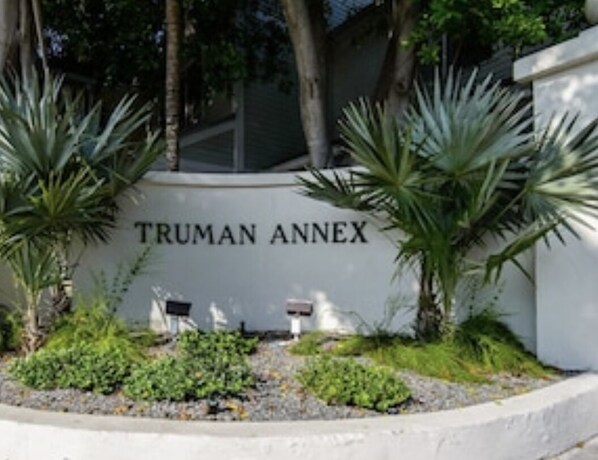 Ein Schild mit der Aufschrift "TRUMAN ANNEX", mit einem begrünten Bereich, der Palmen und Sträucher zeigt.