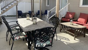 Une terrasse avec une table et des chaises, un canapé et un escalier menant à une maison.