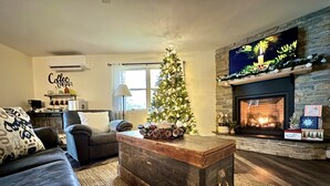 A cozy living room with a fireplace, a Christmas tree, and a coffee bar sign. - Beachfront Breezes 20 Steps To Water w/ Beach Firepit & Grill Near Acadia (Gouldsboro)