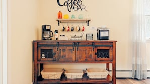 A coffee bar area with a rustic wooden cabinet, a coffee machine, and various mugs and bottles.