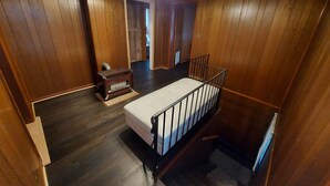 Um quarto com painéis de madeira, uma mesinha, um banco e uma escada.