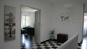 Un couloir doté d’un sol à carreaux noirs et blancs, une carte du monde accrochée au mur et un panneau indiquant des noms en français.