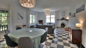 Un coin repas avec une table ronde, des chaises et un sol à carreaux. On y trouve une cheminée, un téléviseur et une lampe sur une table d’appoint.