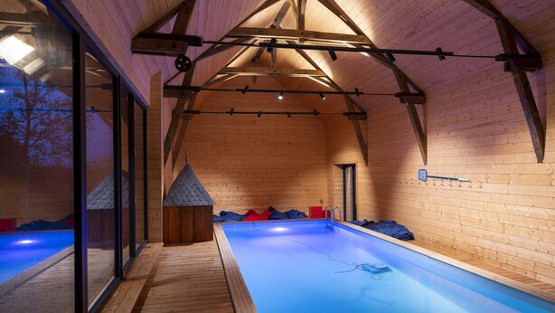 Una piscina interior con vigas de madera y una pared de cristal.