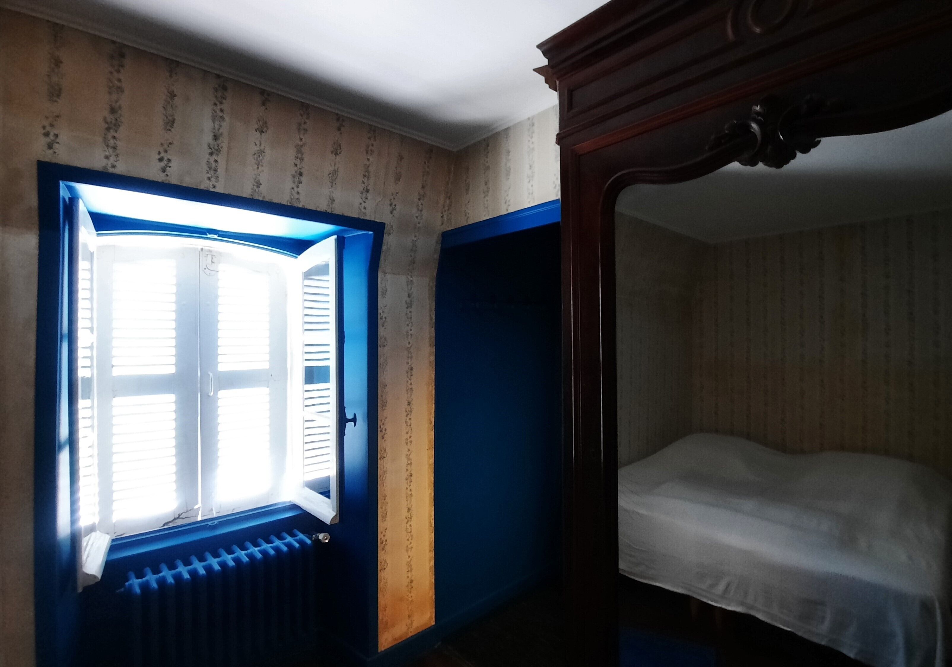 Um quarto com janela, radiador e cama.