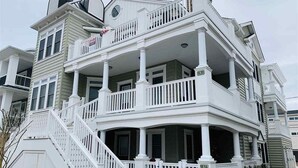 Una casa de varios pisos con un balcón y una escalera, y un cartel de 'For Sale'.