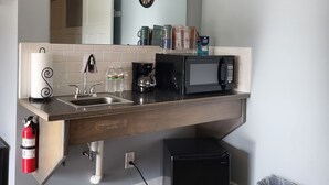 A modern kitchen with a sink, microwave, and coffee maker. There is a fire extinguisher and a trash can. - Downtown by the river (Hesperia)