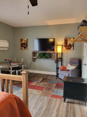 A living room with a flat-screen TV, a dining table with chairs, a sofa, and a small black side table. - Downtown by the river (Hesperia)