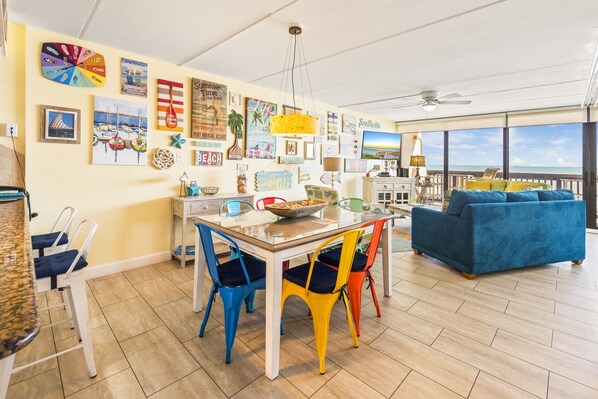 A dining area with a table and chairs, a sofa, and a TV in a room with a view.