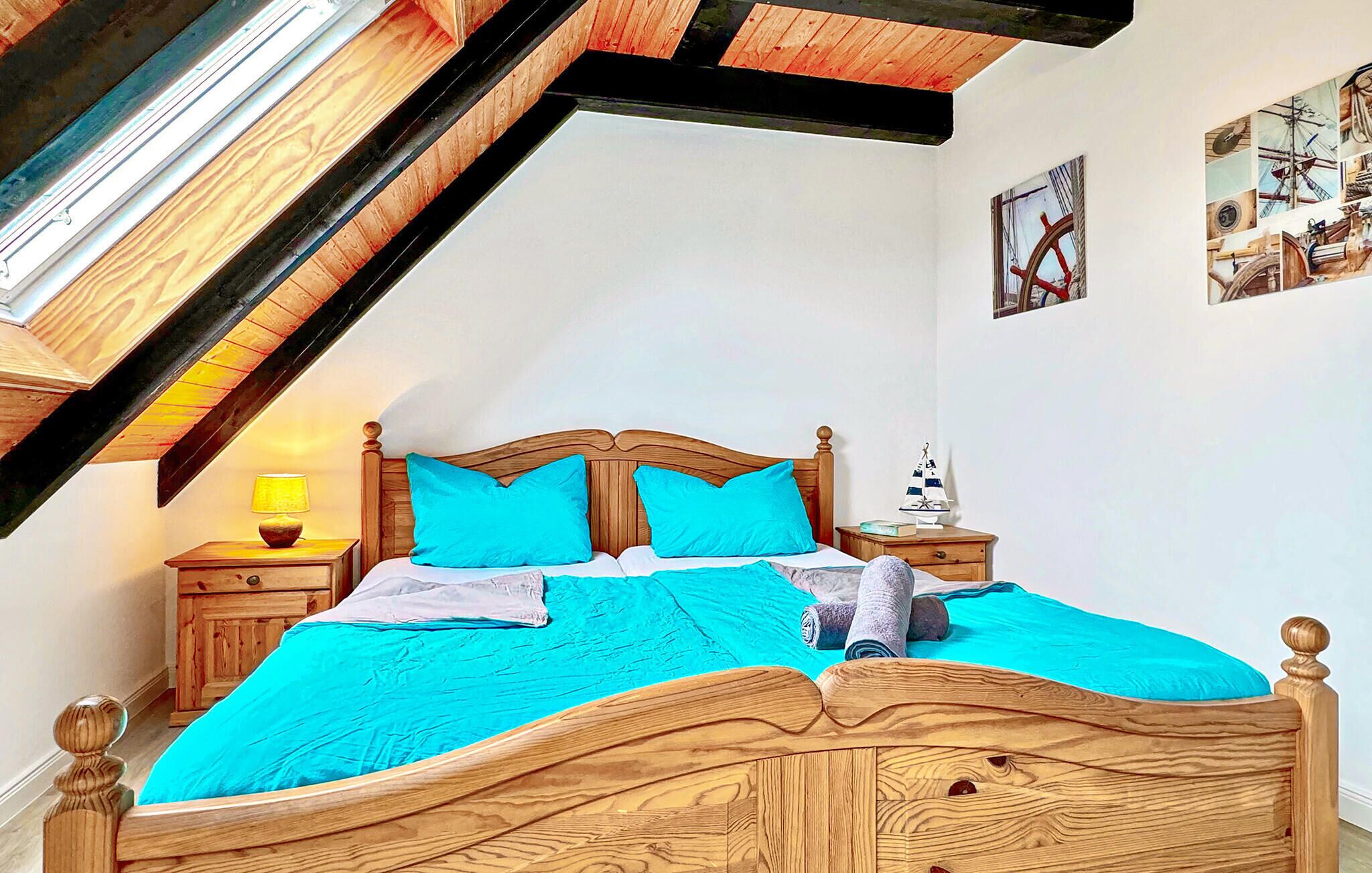 Une chambre avec un plafond en pente, un cadre de lit en bois et un puits de lumière.