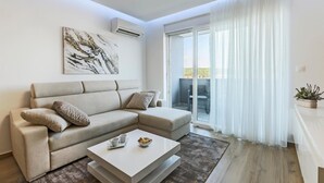 Ein modernes Wohnzimmer mit einer Couch, einem Couchtisch und einem Balkon mit transparenten Vorhängen.