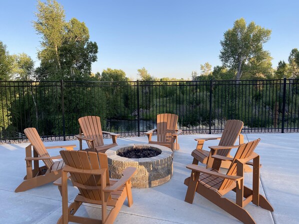 A patio area with Adirondack chairs arranged around a circular fire pit.