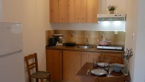 Una cocina compacta con armarios de madera, una mesa de comedor con sillas, una lámpara colgante y un refrigerador.