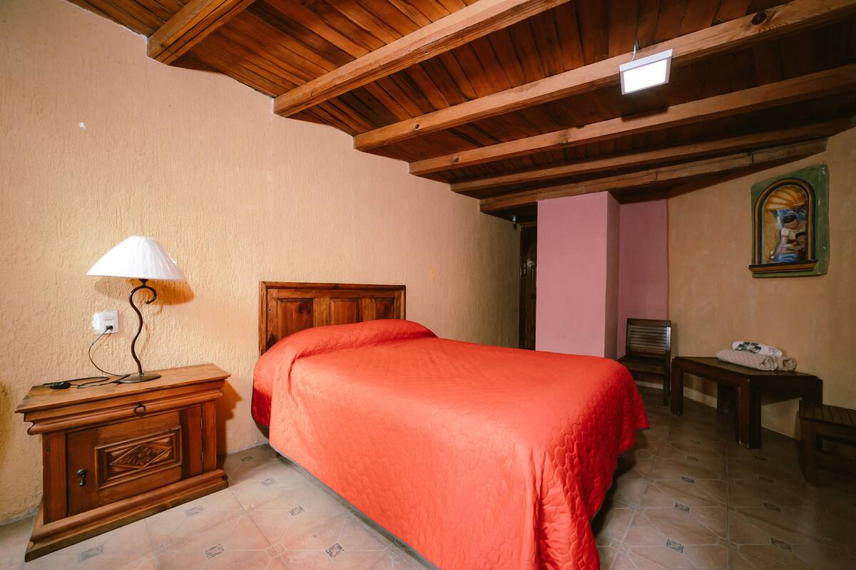 Une chambre à coucher avec un lit en bois, une table de chevet avec une lampe, une petite table et une chaise.