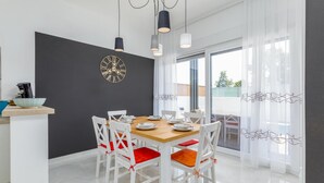 A modern dining area with a black accent wall, a decorative clock, and a view of the outdoors through large windows. - Beach front home in Peroj (Peroj)