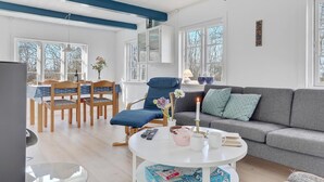 A bright living room with a sofa, chairs, a dining table, and a TV. - Lovely home in Gudhjem with WiFi (Gudhjem)