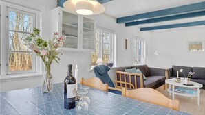 A modern living room with a dining table, a sofa, and a chair. There is a bottle of wine on the table. - Lovely home in Gudhjem with WiFi (Gudhjem)