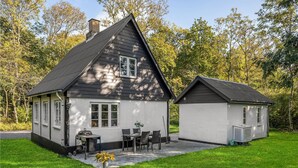 A two-story house with a patio area, a small table, and chairs. - Lovely home in Gudhjem with WiFi (Gudhjem)