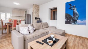 Un salon moderne avec un canapé beige, une table basse avec une télécommande et un tableau représentant une statue accroché au mur.