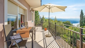 Un balcon avec une table, des chaises et un grand parasol.