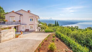 Une maison à deux étages dotée d’un balcon donnant sur un vignoble et un lac.