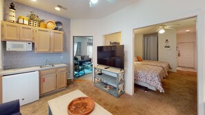 A compact living space with a kitchenette, a TV, a dining area, and a bedroom. - Light and bright 1st floor condo in Sunset Beach | RC 1802 (Sunset Beach)