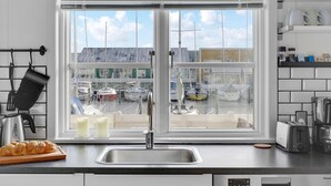 Eine Küche mit einem großen Fenster mit Blick auf eine Marina, einem Spülbecken, einem Toaster und einem Brotlaib auf der Arbeitsfläche.