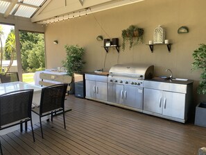 Una cucina esterna con barbecue, pensili e piante pensili.