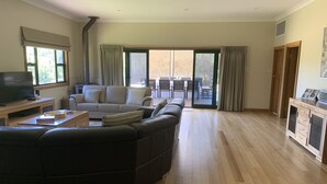 A spacious living room with a large sectional sofa, a television, and a dining area with a table and chairs. - Resort style home set among boutique vineyards. (Summertown)