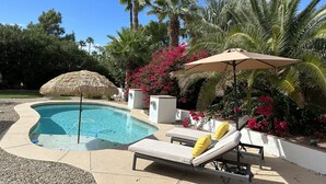 A swimming pool with lounge chairs and umbrellas, surrounded by palm trees and flowering plants. - 2 Master Bedrooms, Luxury beds, Pool & Hot Tub, Large TVs, Surround Sound (Scottsdale)