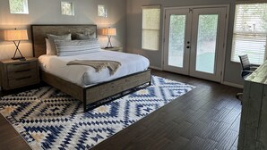 A bedroom with a bed, two bedside tables, a ceiling fan, and a large window with blinds. - 2 Master Bedrooms, Luxury beds, Pool & Hot Tub, Large TVs, Surround Sound (Scottsdale)