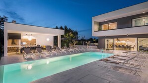 A modern outdoor pool area with lounge chairs and a dining area. - Beautiful home in Sivati with sauna (Sivati)