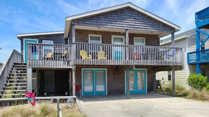A two-story building with a balcony, a staircase, and a door with a red sign. - Shore Beats Work! (2040 Sq ft) (Kill Devil Hills)