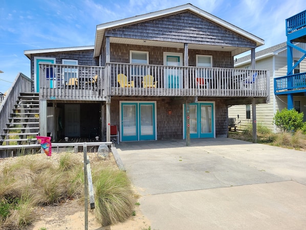 A two-story building with a balcony, a staircase, and a door with a red sign. - Shore Beats Work! (2040 Sq ft) (Kill Devil Hills)