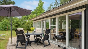 An outdoor patio with a table and chairs, a grill, and a large umbrella. - Gorgeous home in Glesborg with kitchen (Glesborg)
