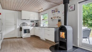 A modern kitchen with white cabinets, a built-in oven, a stove, and a wood-burning stove. - Gorgeous home in Glesborg with kitchen (Glesborg)