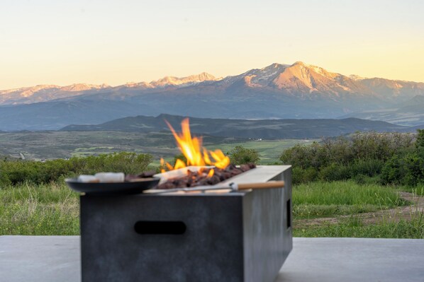 A portable barbecue grill with a fire, set against a backdrop of mountains and a clear sky. - Hot Tub & Sauna Spa, Amazing Mountain Views, Remote Nature Getaway For Families (Glenwood Springs)