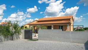 Une maison à deux étages, avec un toit en tuiles, un mur en béton et une allée gravillonnée.