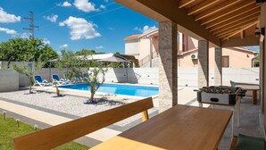 Un espace aménagé au bord de la piscine, avec une table en bois, des chaises longues et une table de baby-foot.