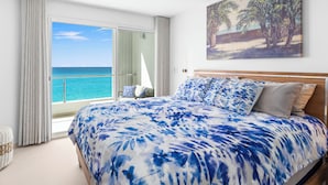 Un dormitori amb un llit, un ventilador de sostre, un quadre i vista a l'oceà.