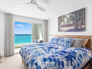 Ein Schlafzimmer mit einem Bett, einem Deckenventilator, einem Gemälde und Blick aufs Meer.